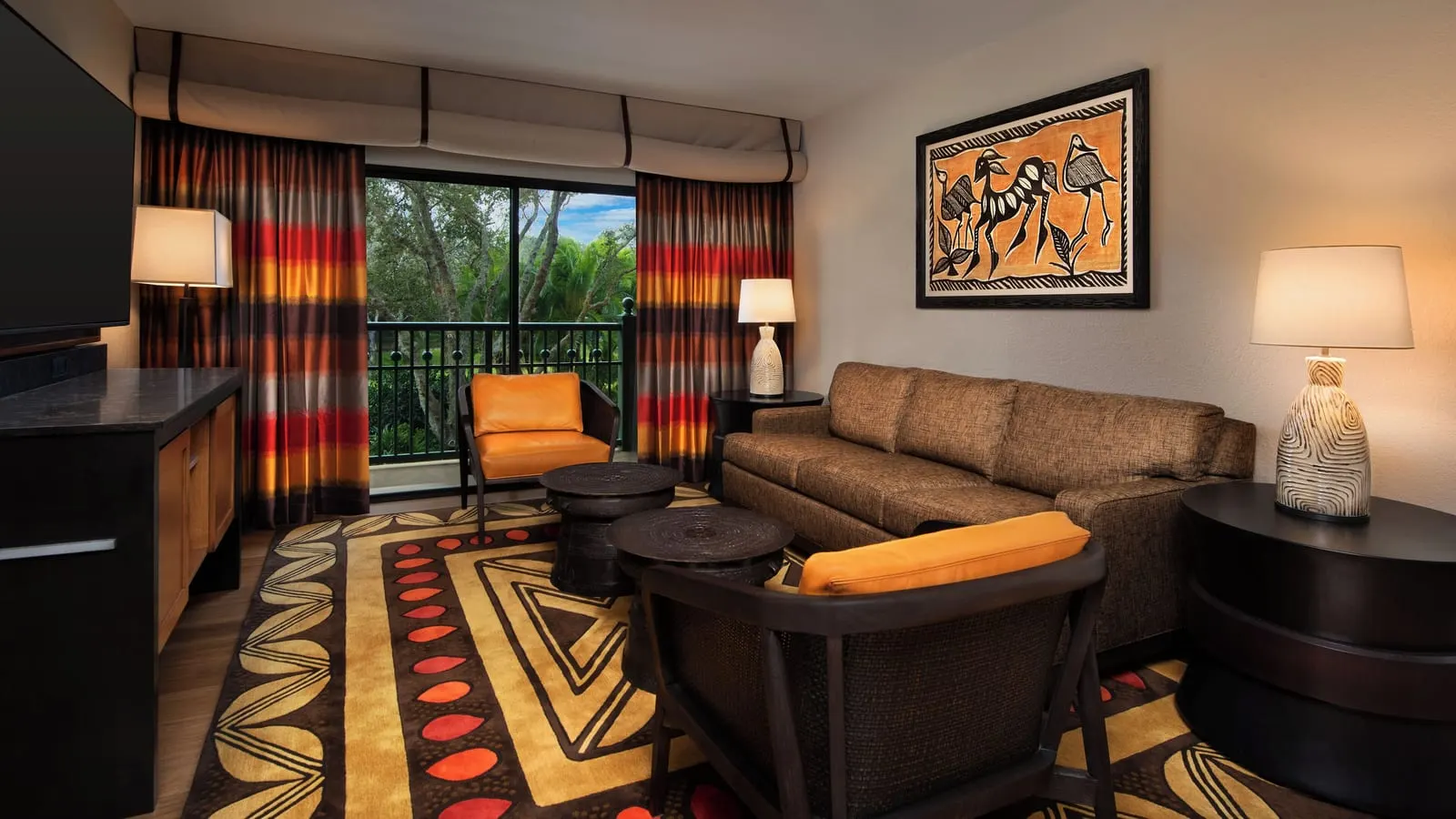2 Bedroom Club Level Suite at Disney's Animal Kingdom Lodge: the living room, with a sofa, two armchairs and two round low tables on a patterned rug, and a glass door onto the balcony
