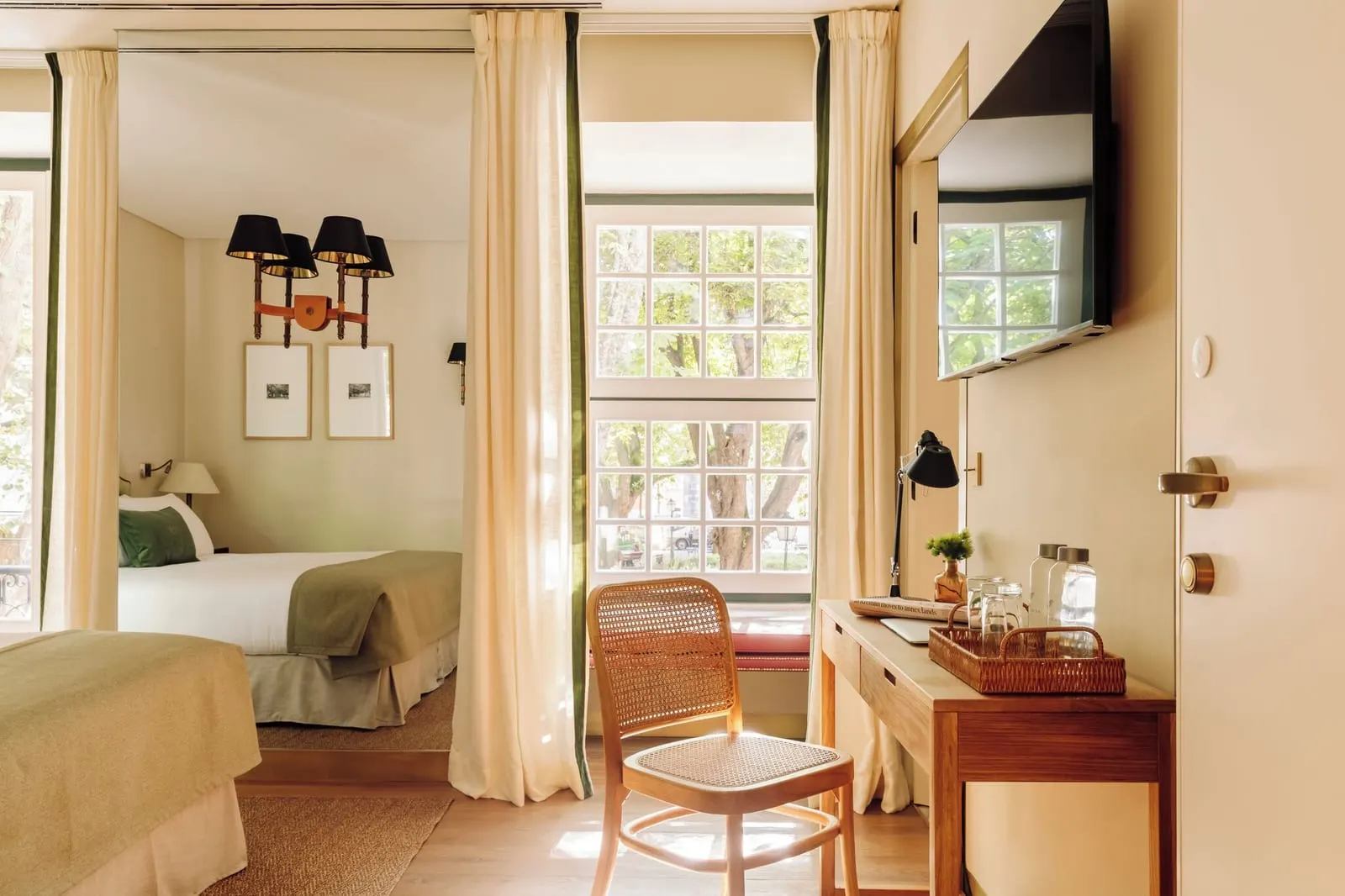 Deluxe Garden View room at Hotel das Amoreiras: a desk and cane chair beside a tall window with trees outside