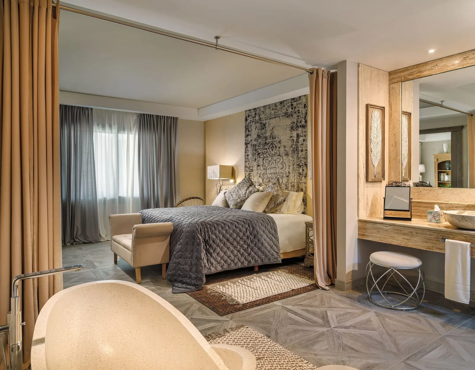One-bedroom River Villa at Royal River: the bedroom seen past the freestanding bath, with a vanity and mirror