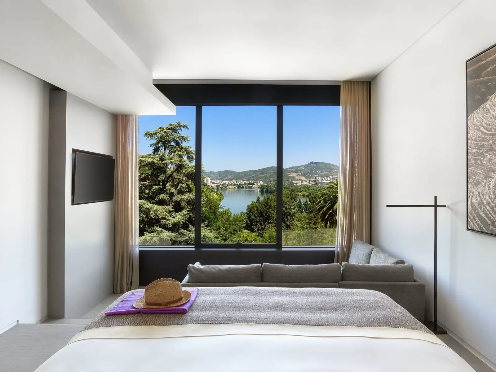 Quinta River at Six Senses Douro Valley: the bed facing a picture window over the Douro, with a sofa below the glass