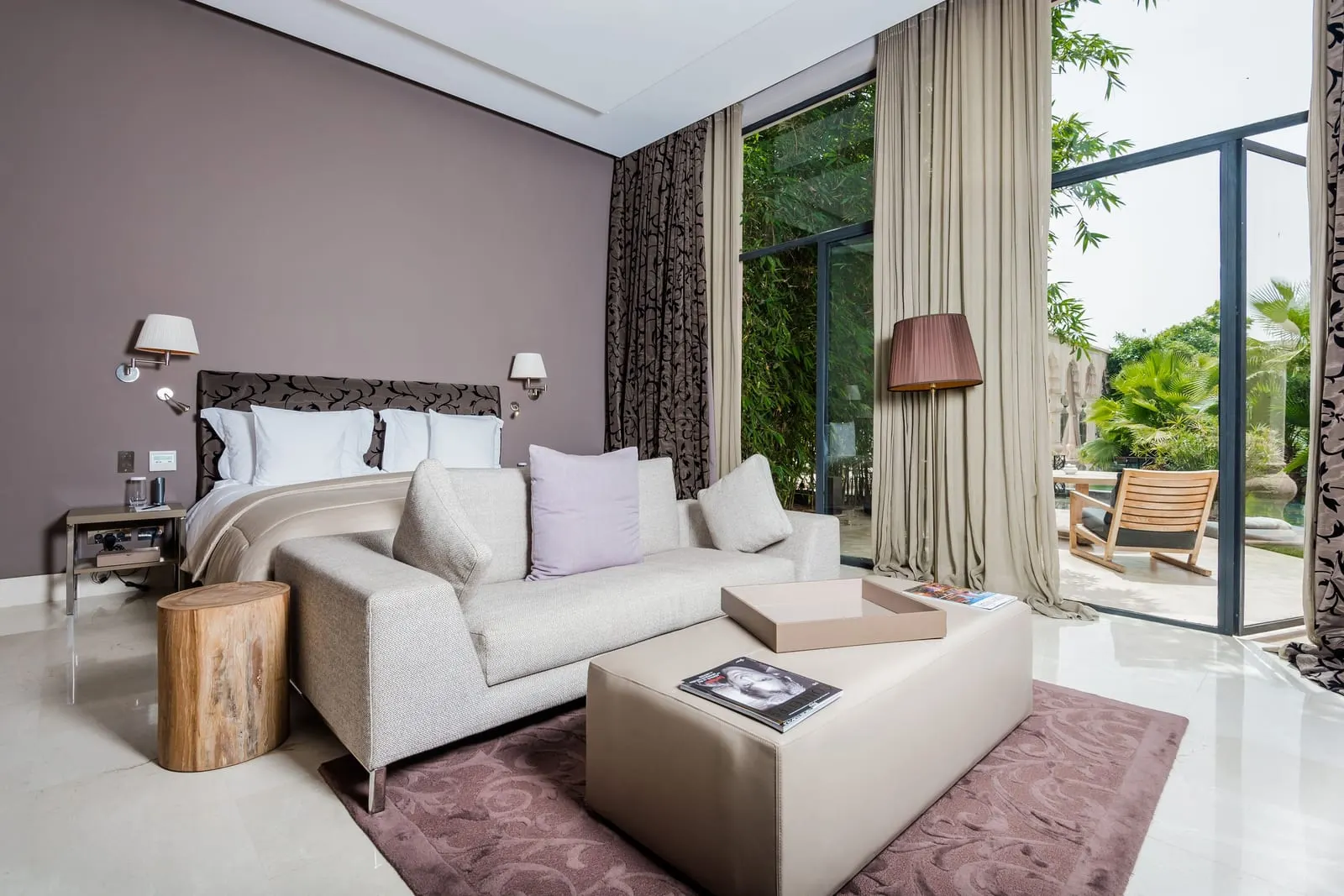 Two-Bedroom Pool Suite at Palais Namaskar: a bedroom with a white sofa at the foot of the bed and glass doors onto a garden terrace