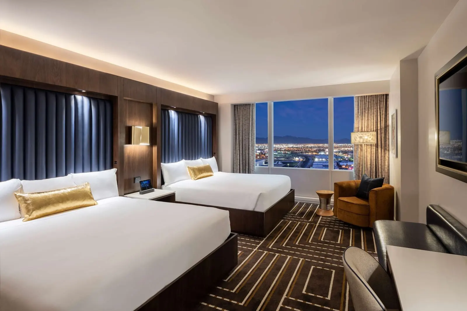 Double King al Circa Resort & Casino: due letti king con testiere imbottite blu, una poltrona arancione e un'ampia finestra sulla città di notte