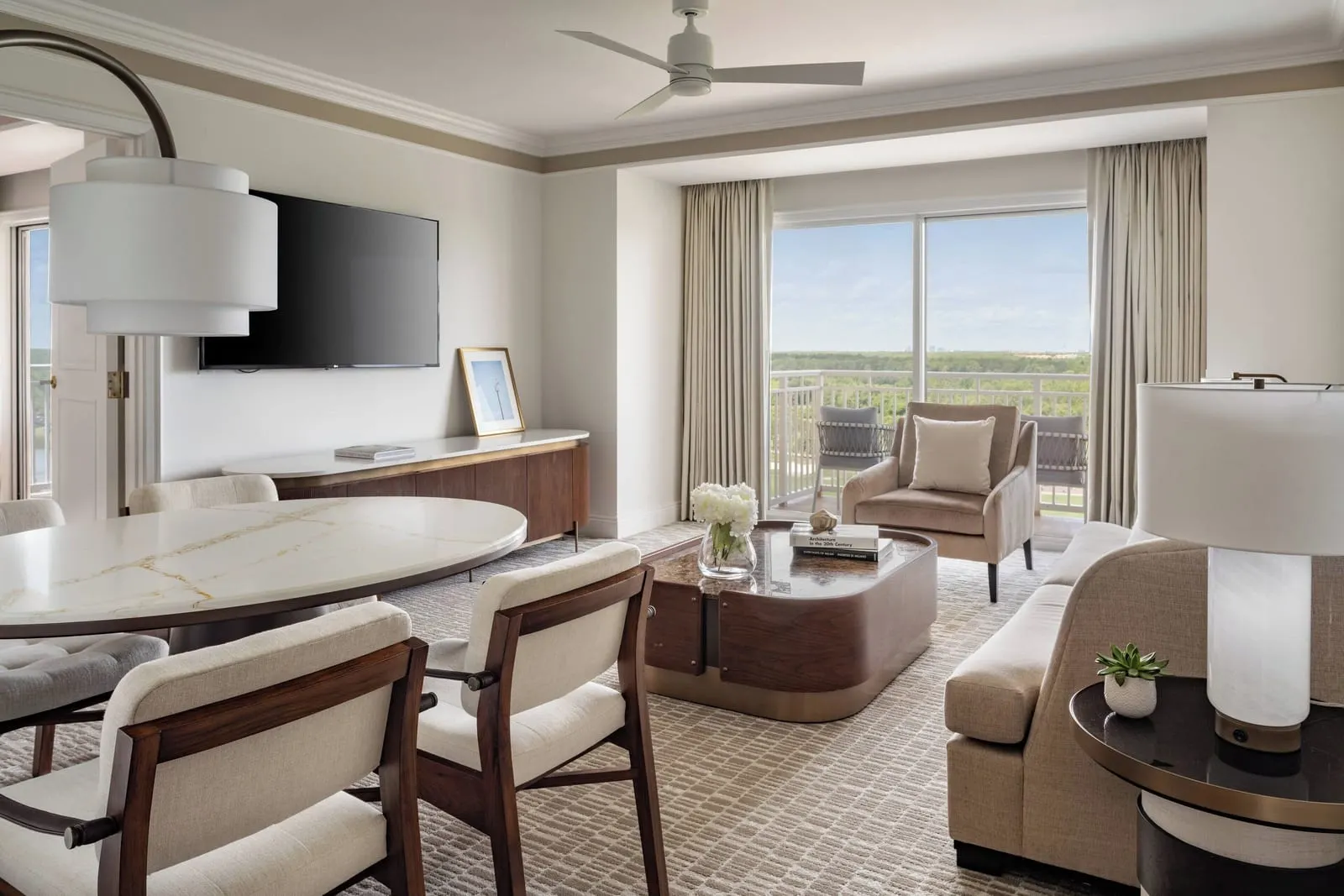Executive Suite at The Ritz-Carlton Orlando, Grande Lakes: the living room, with a sofa, an armchair, a dining table for four and a sliding door onto the balcony