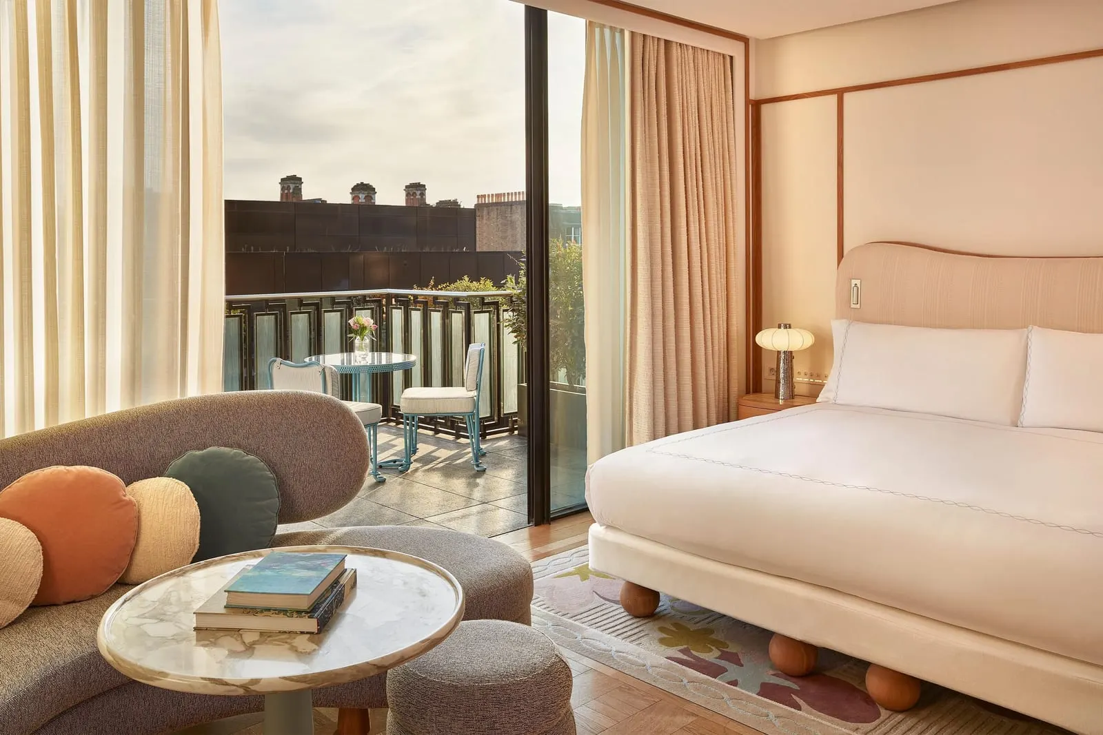 Mayfair Balcony Room at Claridge's: the bed, a curved sofa and an open glass door to the balcony with a table and chairs