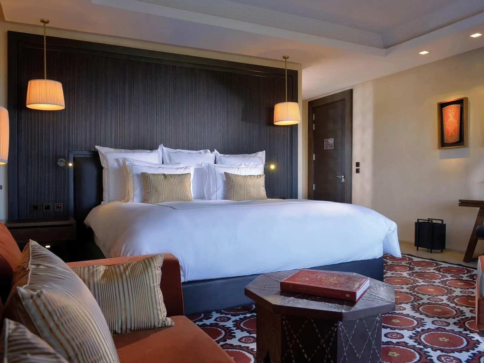 Junior Suite Atlas View at Fairmont Royal Palm Marrakech: a king bed against a dark panelled headboard with pendant lamps and a patterned red rug