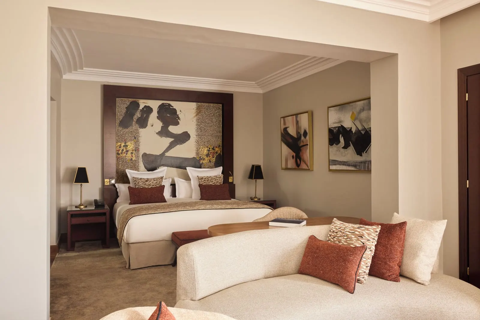 Deluxe Junior Suite at Nobu Hotel Marrakech: a curved cream sofa with red cushions at the foot of the king bed