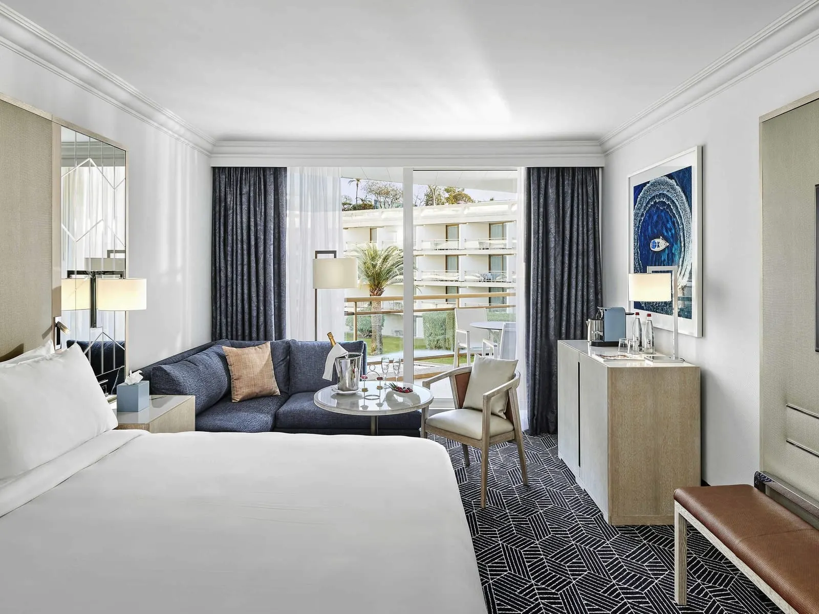 Fairmont Garden View room at Fairmont Monte Carlo: the bed, a sofa and a window onto the terrace and the garden courtyard