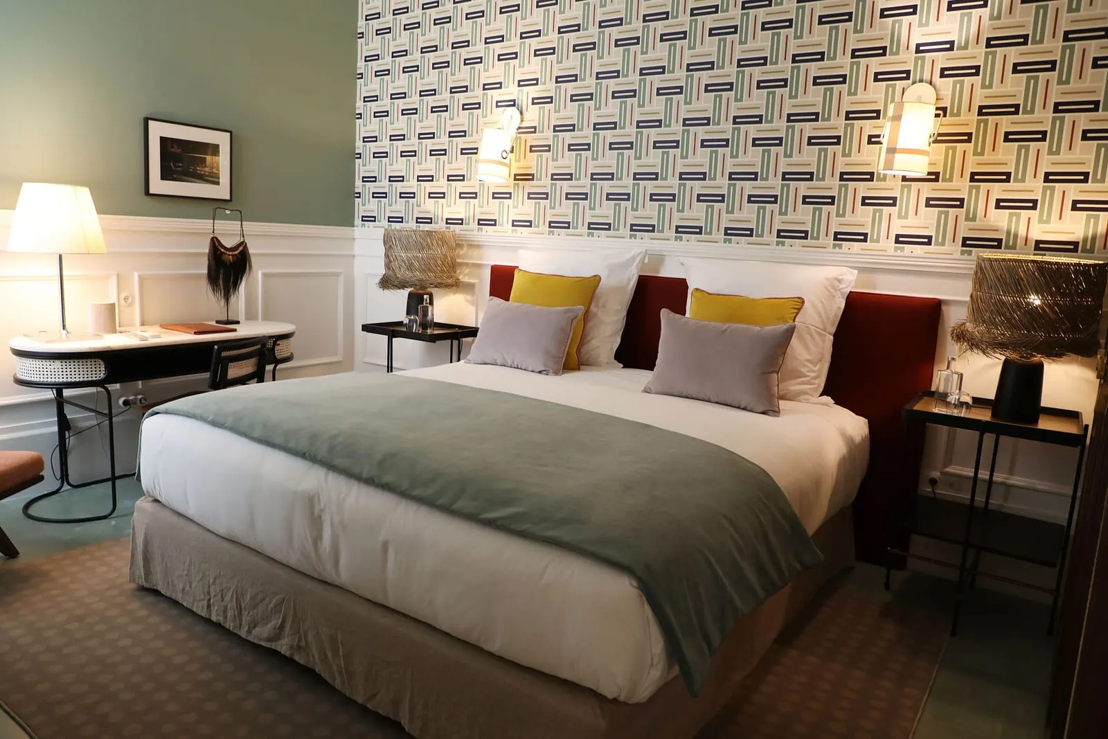 Pateo Room at Sublime Lisboa: the bed against geometric wallpaper, with a desk and lamp beside it