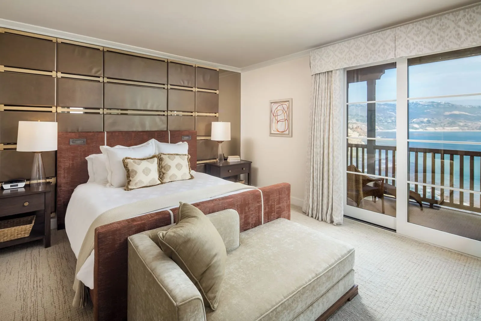 Vanderlip Suite at Terranea Resort: a bed with a padded headboard and a chaise at its foot, beside glass doors onto a balcony overlooking the coast