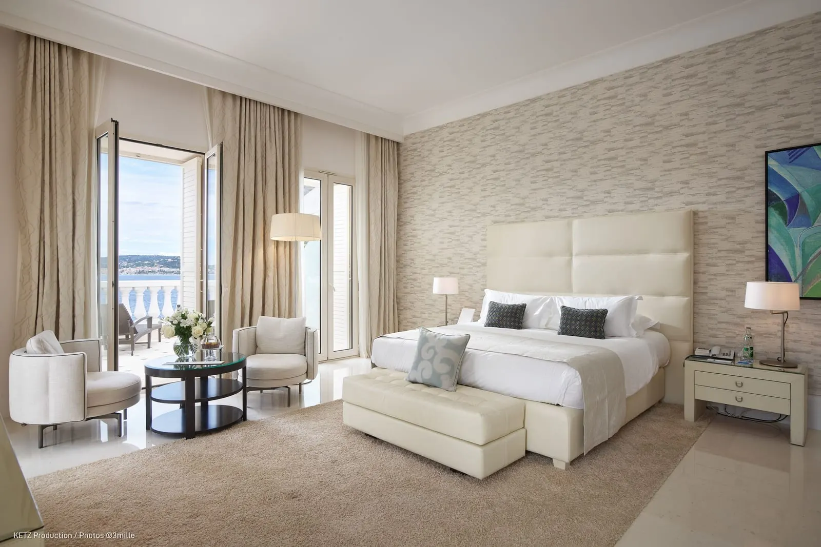 Superior Junior Suite 220 at Cap Estel: the bed with a bench, a sitting area and French windows to the sea