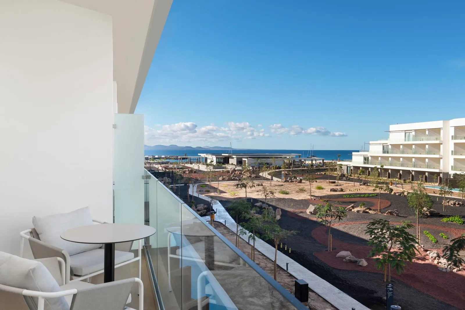 Superior Side Sea View at Barceló Playa Blanca: a balcony with a small table and a partial view of the sea past the neighbouring wing