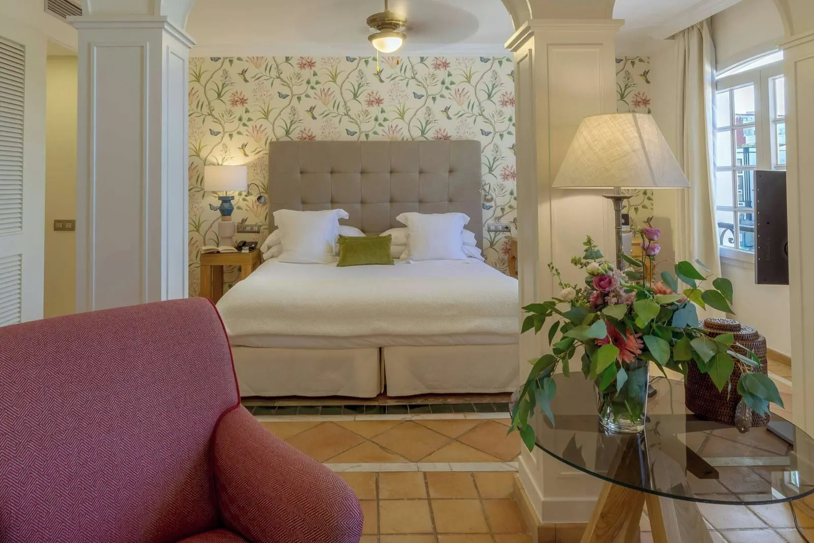 Casas Ducales Junior Suite at Bahía del Duque: the bed in an alcove framed by columns, seen from the sitting area