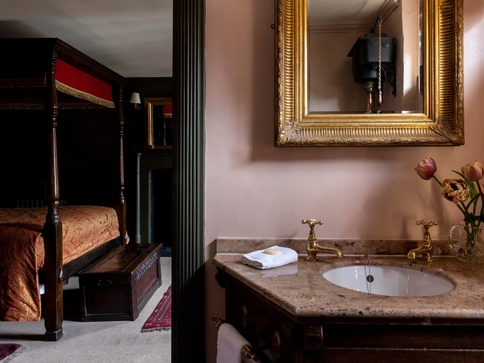 Bagno di Superior Double al Hazlitt's: un lavabo in marmo sotto uno specchio dorato, con il letto a baldacchino visibile attraverso la porta