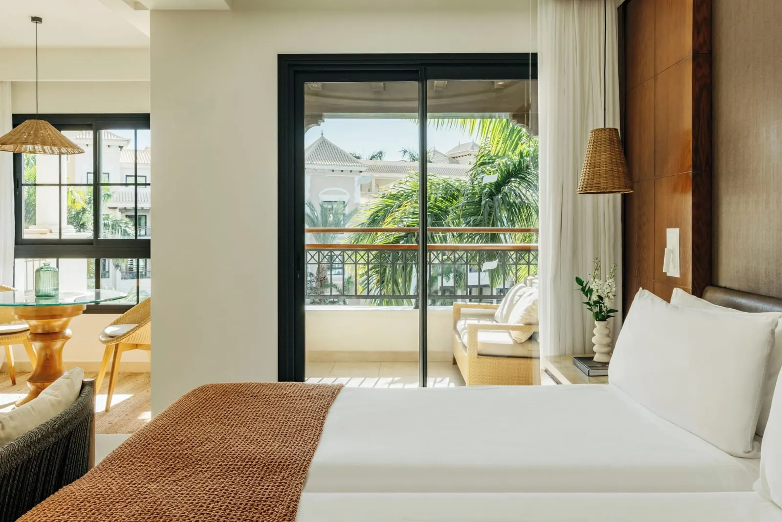 Deluxe Resort View at Gran Meliá Palacio de Isora: the bed and an open balcony door onto palms and resort buildings