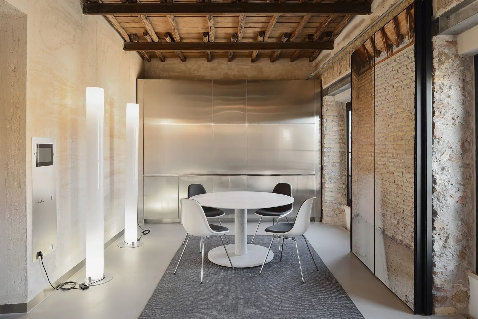 Suite Apartment Double at Rhinoceros Roma: a round dining table before a steel kitchen wall, under a beamed ceiling