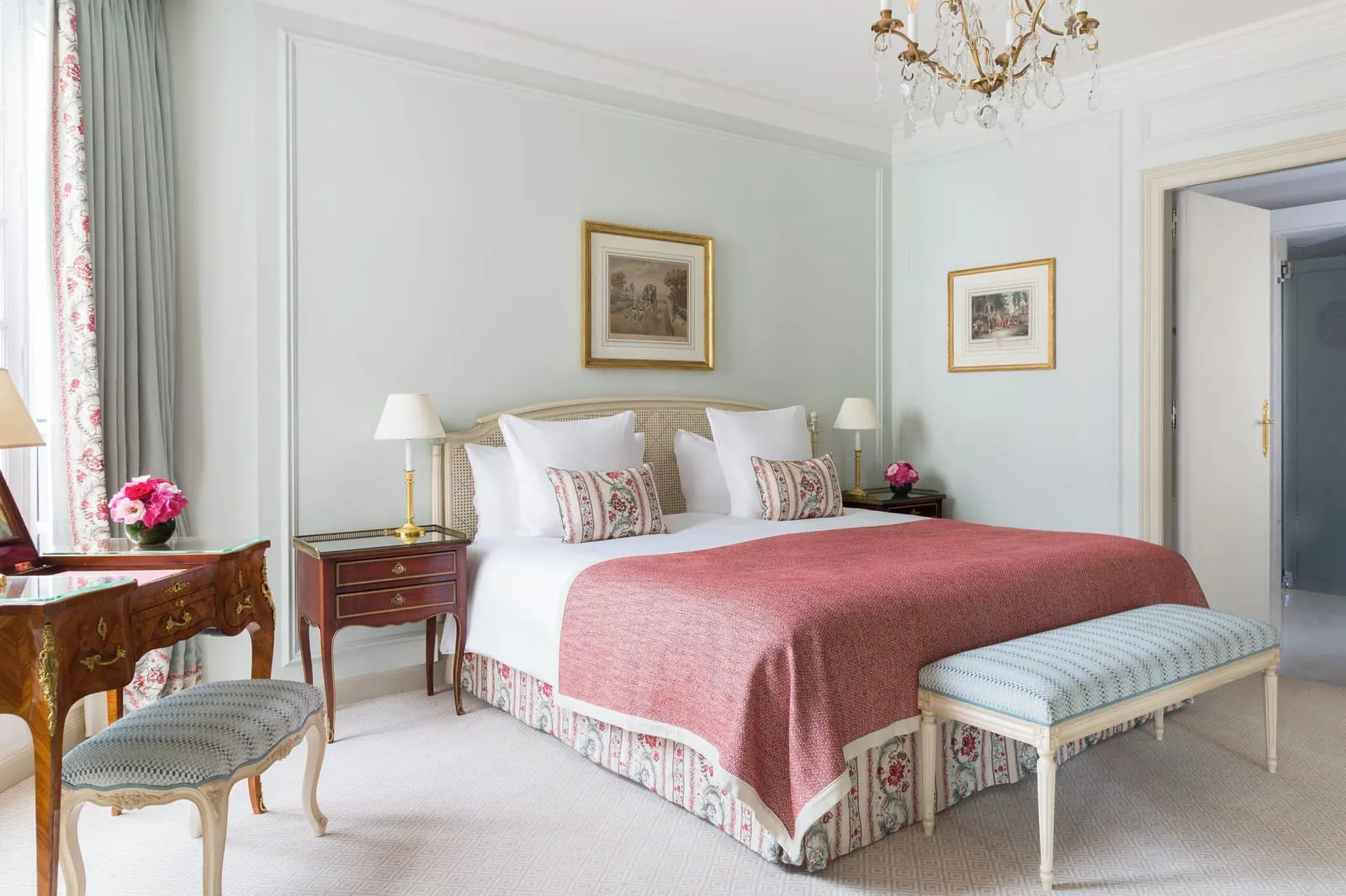 Deluxe Terrace Suite at Le Bristol Paris: a bed with a raspberry throw and a striped bench, an inlaid writing desk with a stool, and pale green panelled walls