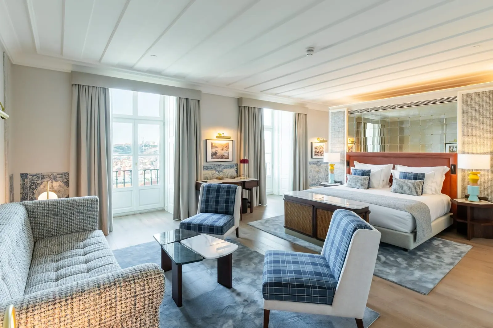 Ludovice Prestige at Palácio Ludovice: a sofa and tartan armchairs, the bed against a mirrored wall and tall windows