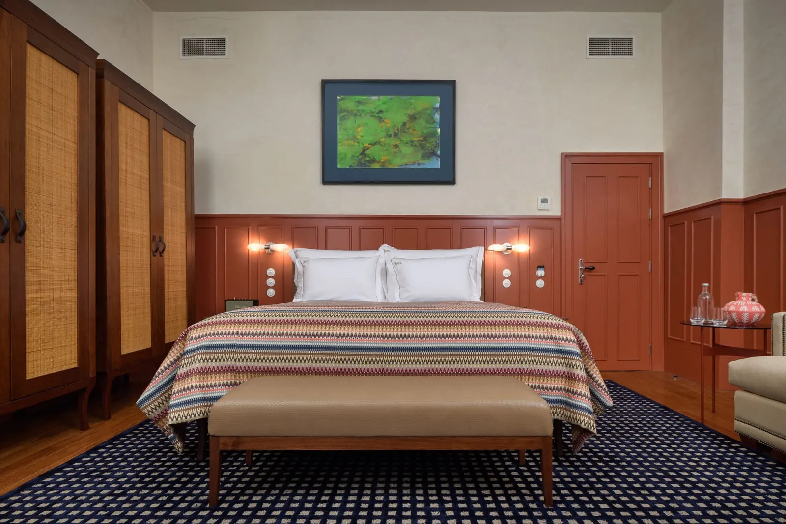 Prestige Chiado room at Bairro Alto Hotel: the bed with a bench at its foot, tall woven-front wardrobes and red panelling