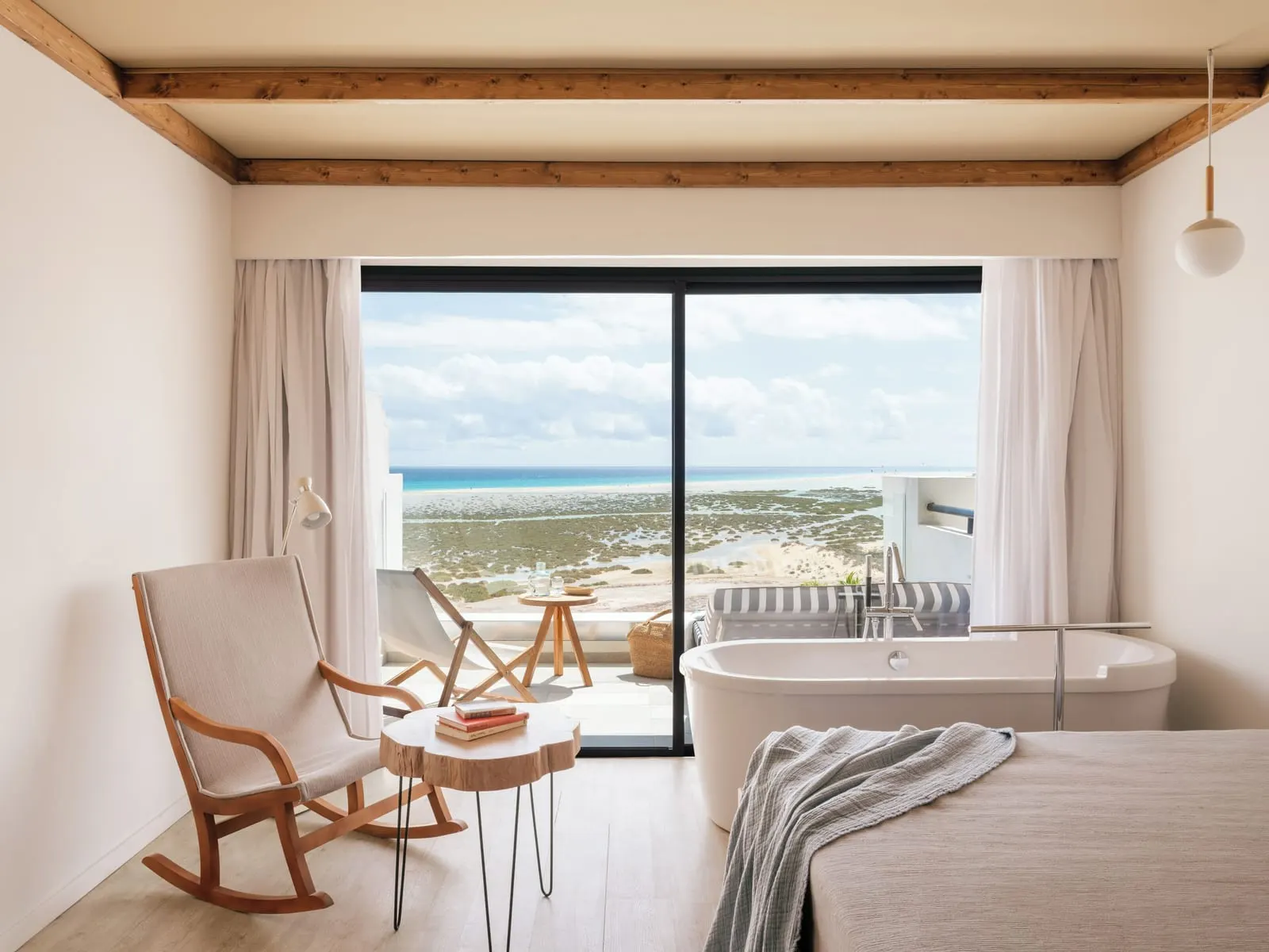 Zel Suite Ocean View at ZEL Fuerteventura: a freestanding bathtub beside the bed, in front of a glass wall onto a terrace over the ocean