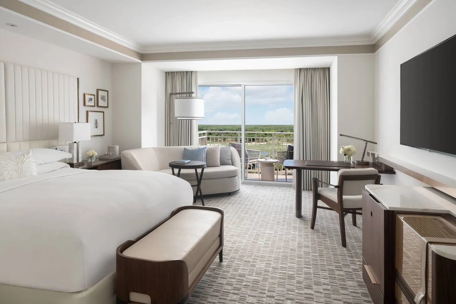 Lake View room at The Ritz-Carlton Orlando, Grande Lakes: a king bed, a curved sofa, a writing desk and a sliding door onto the balcony