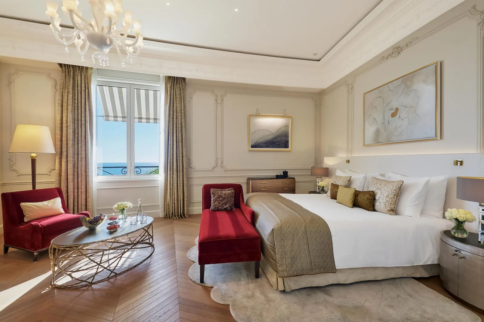 Exclusive Room with sea view at Hôtel de Paris Monte-Carlo: the bed, a red chaise longue and armchair, and a window to the sea