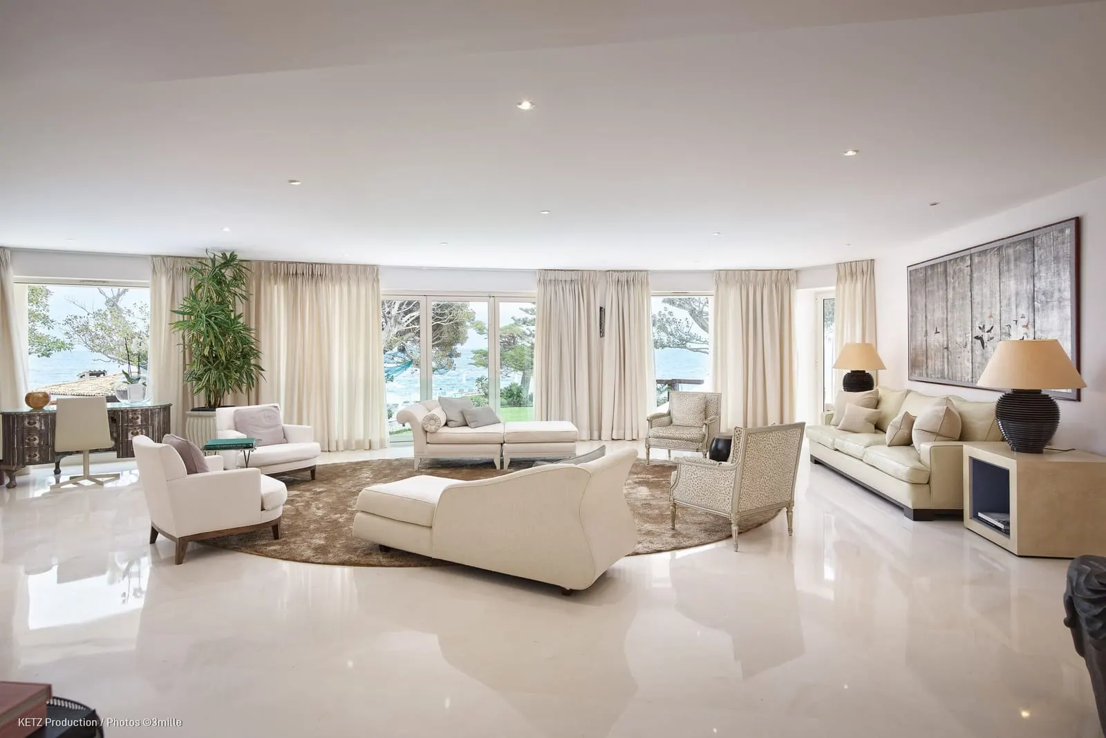 Presidential Suite 110 at Cap Estel: the living room with sofas and windows along the garden
