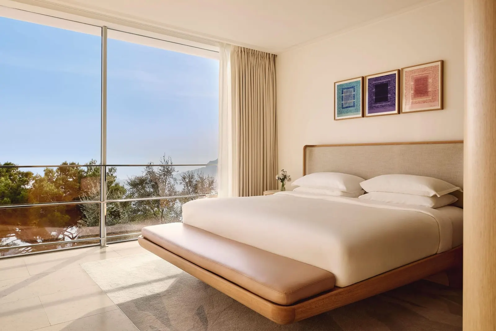 Sea View Duplex Suite at The Maybourne Riviera: the bedroom with a wide window over the trees to the sea