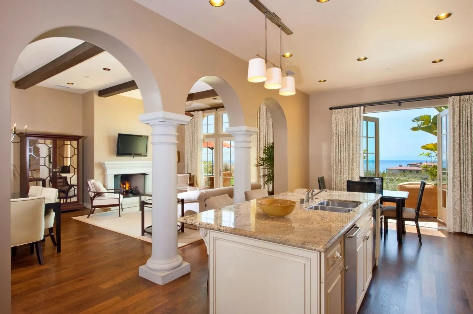 Four-Bedroom Villa at Terranea Resort: an open kitchen with a granite island and archways through to a living room with a fireplace and doors to a terrace