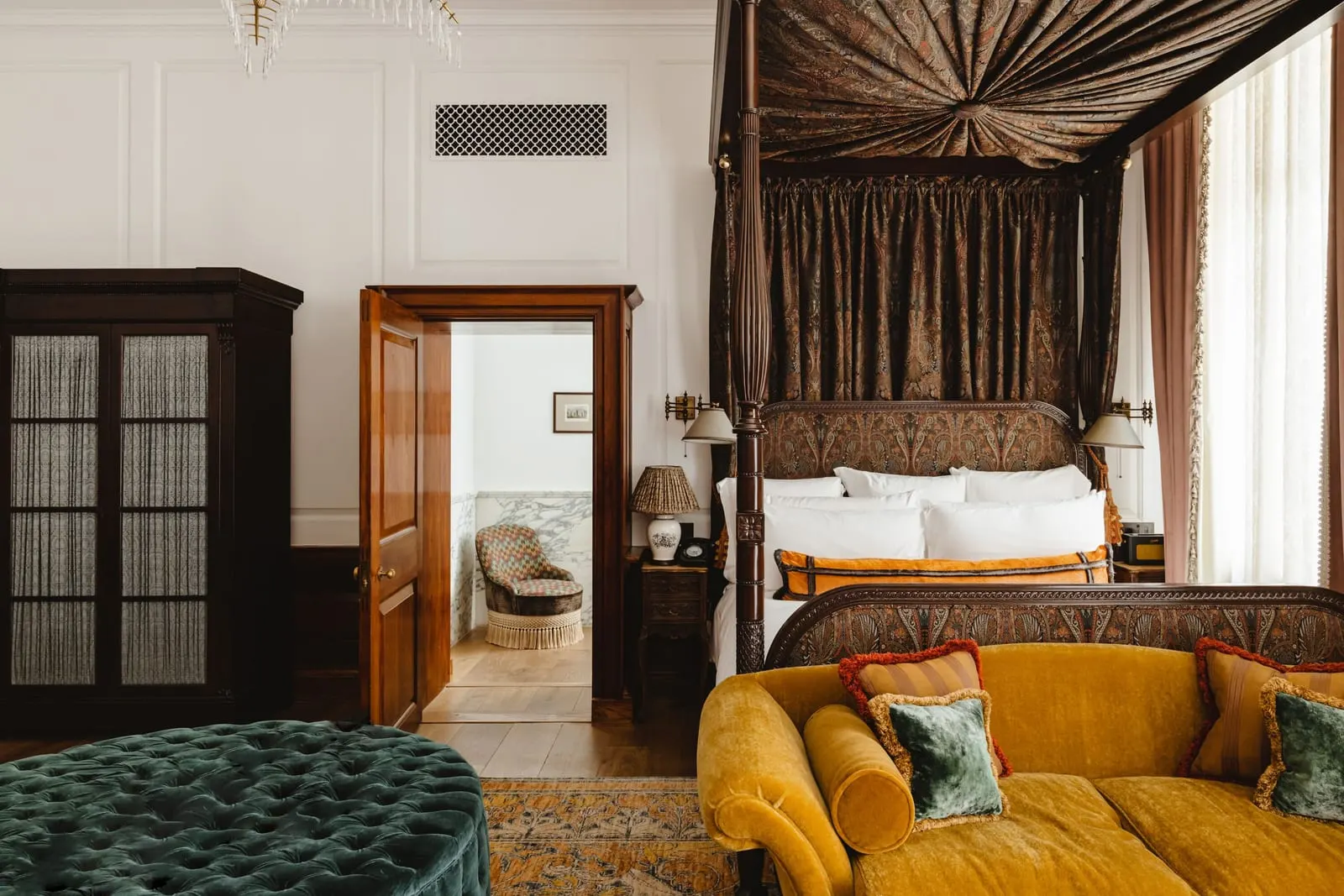 Terrace Suite at The Ned: a four-poster bed with a pleated canopy, a yellow velvet sofa and a wardrobe