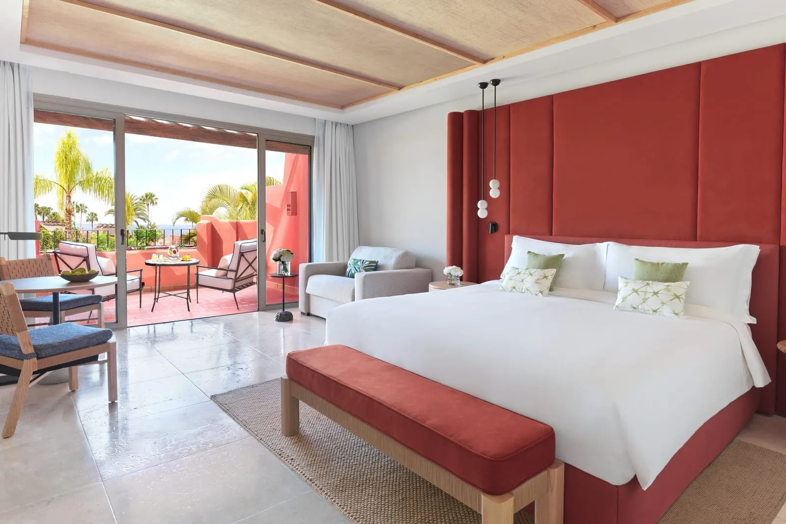 Retreat Deluxe Room Ocean View at the Ritz-Carlton Abama: a king bed, a red bench and a sofa by doors to the terrace
