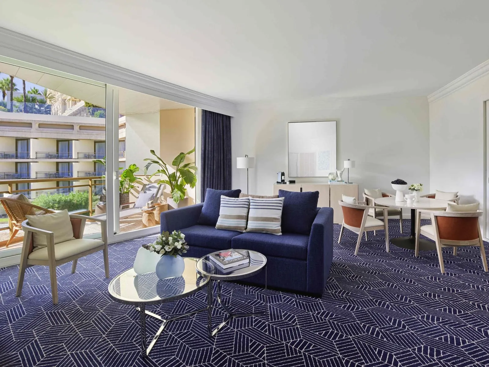 Garden Suite at Fairmont Monte Carlo: the living room with a sofa, a dining table and the garden courtyard outside