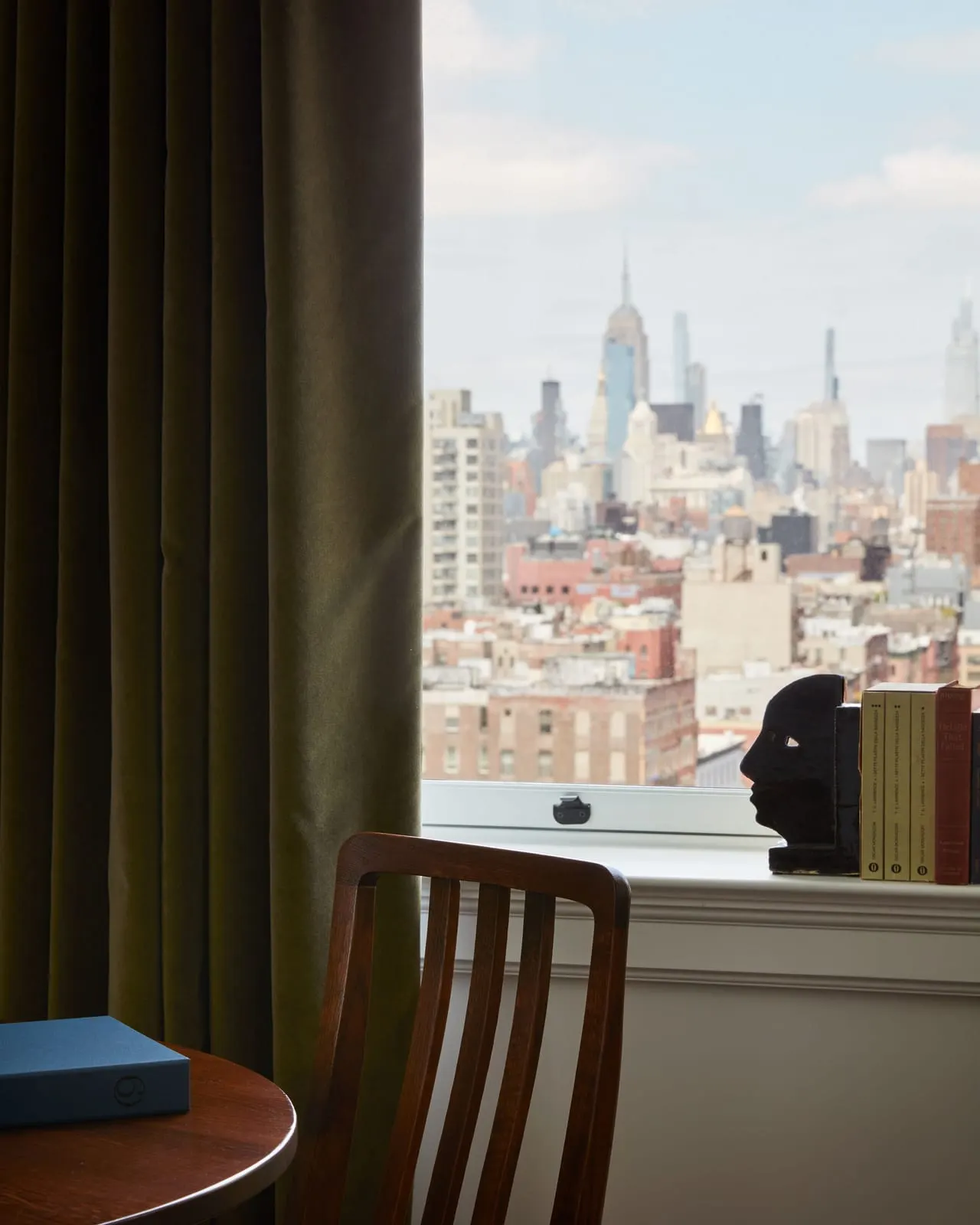 Supreme View King Suite at Nine Orchard: the view from a window past an olive curtain, over low rooftops to the city skyline