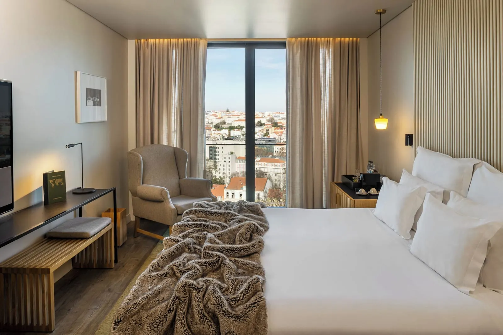 Superior City View Room at Memmo Príncipe Real: the bed, an armchair, a desk and a tall window over the city