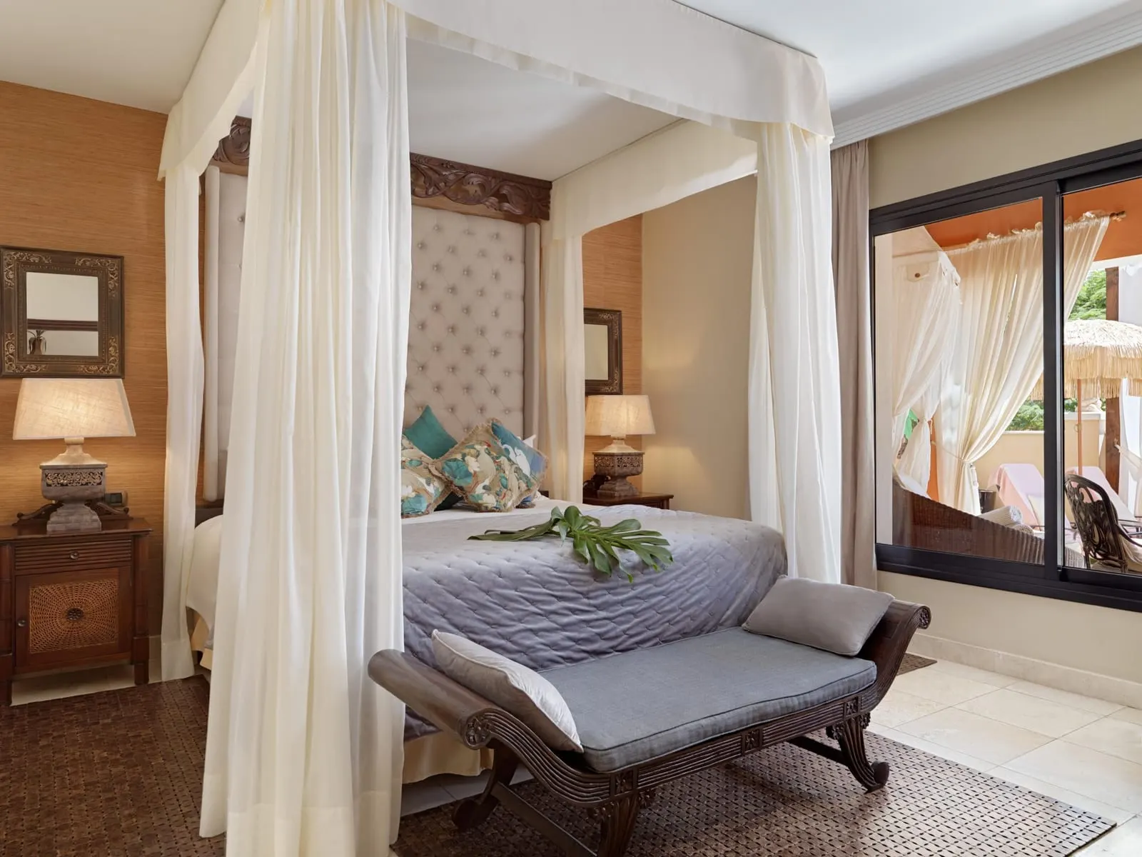 Duchess Villa at Royal Garden Villas: a four-poster bed with white drapes, a carved bench and doors to the terrace