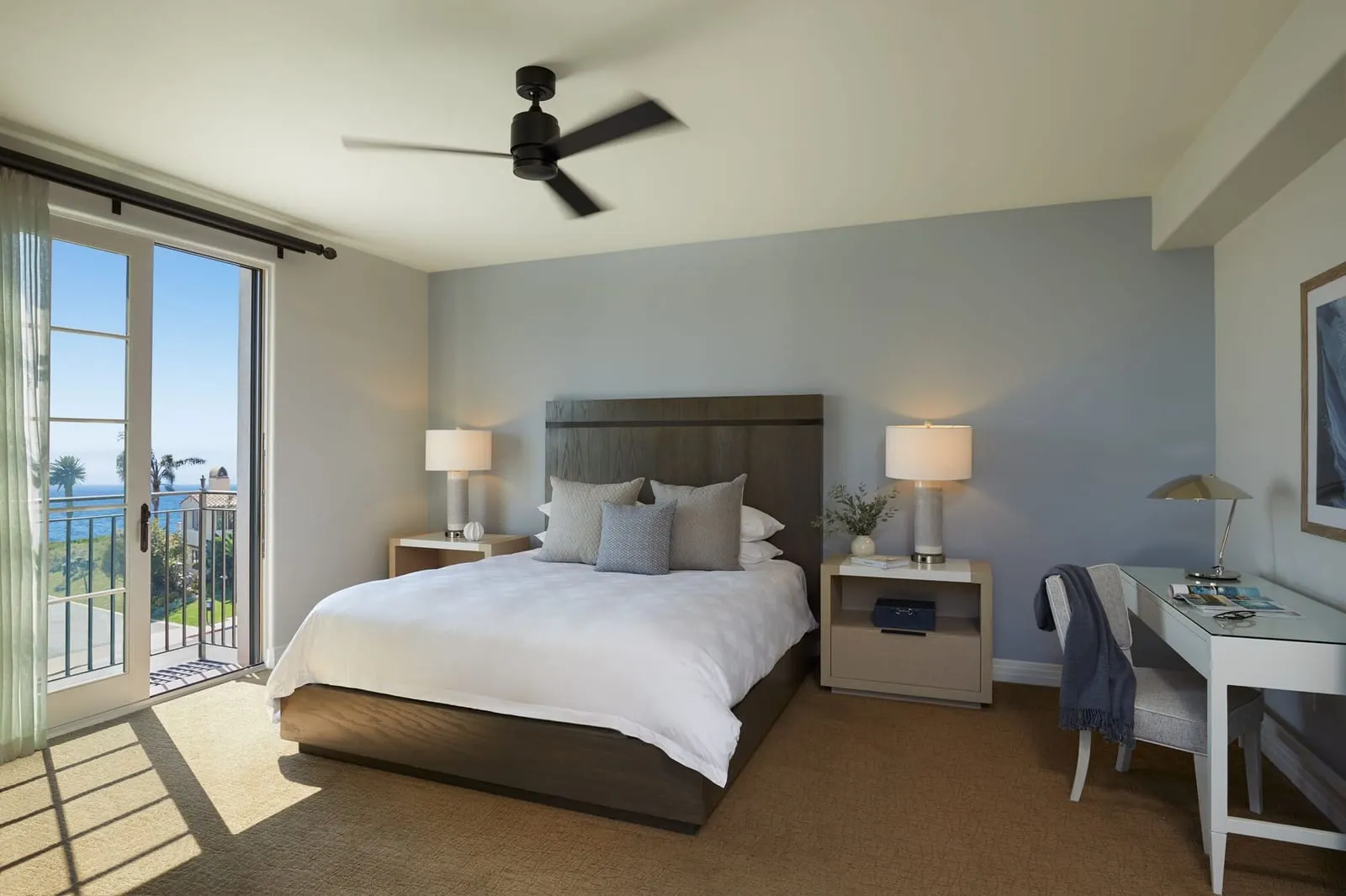 One-Bedroom Casita, Resort View at Terranea Resort: a bed with a dark headboard, a white writing desk and glass doors onto a balcony, with a ceiling fan above