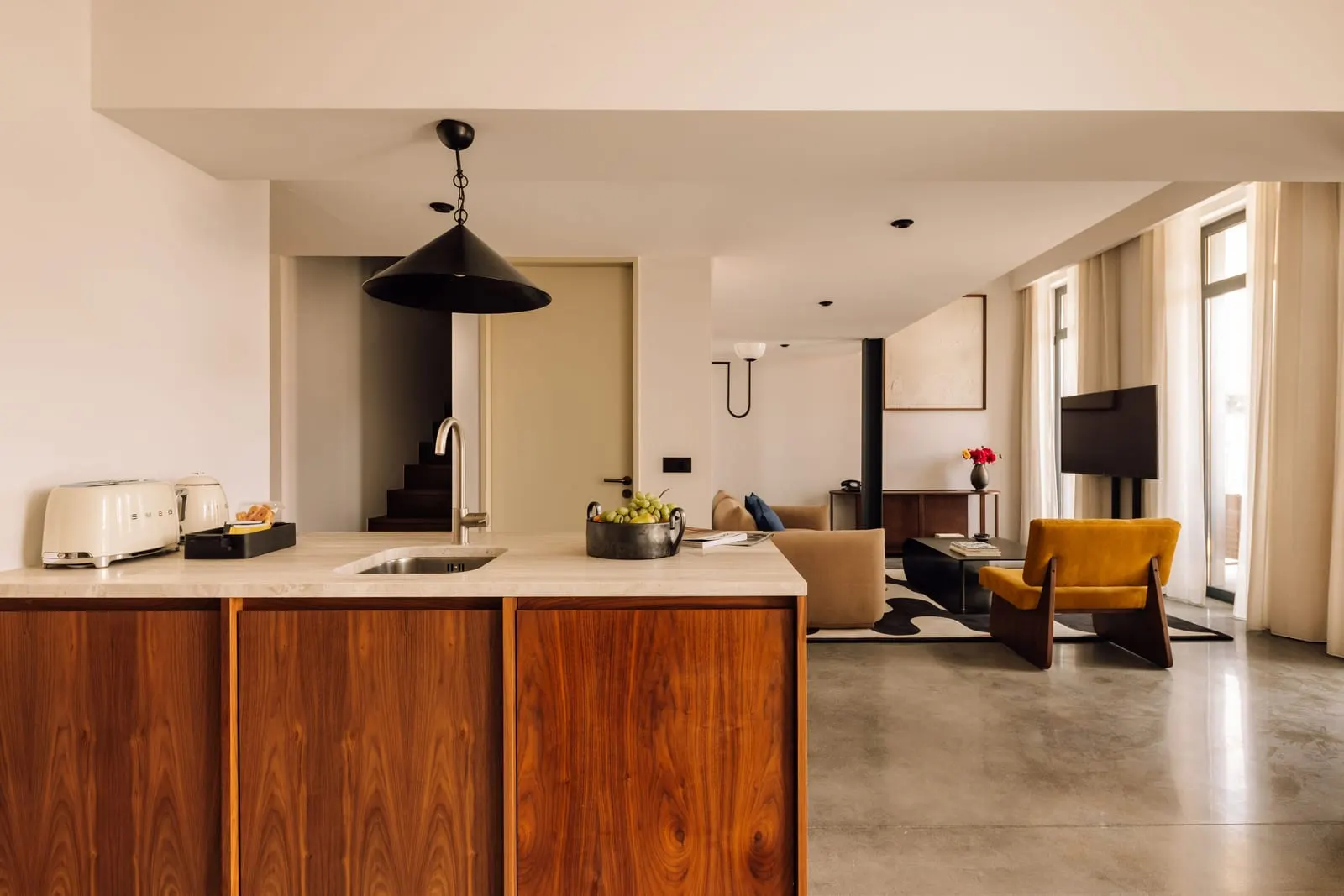 Two Bedroom Duplex River Suite at The Rebello: the kitchen island, with the living room and tall windows beyond