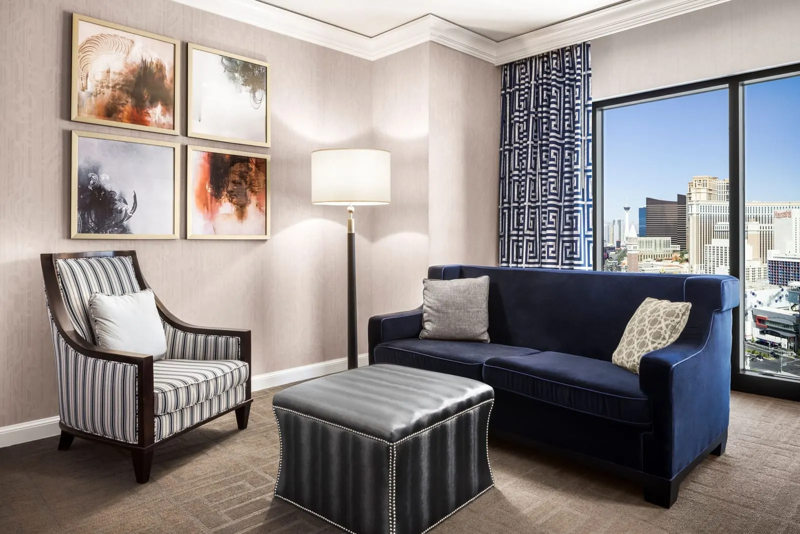 Augustus Strip View Room im Caesars Palace, wie das Zimmer vor dem Umbau 2026 aussah: ein blaues Sofa, ein gestreifter Sessel, ein Lederhocker und ein hohes Fenster
