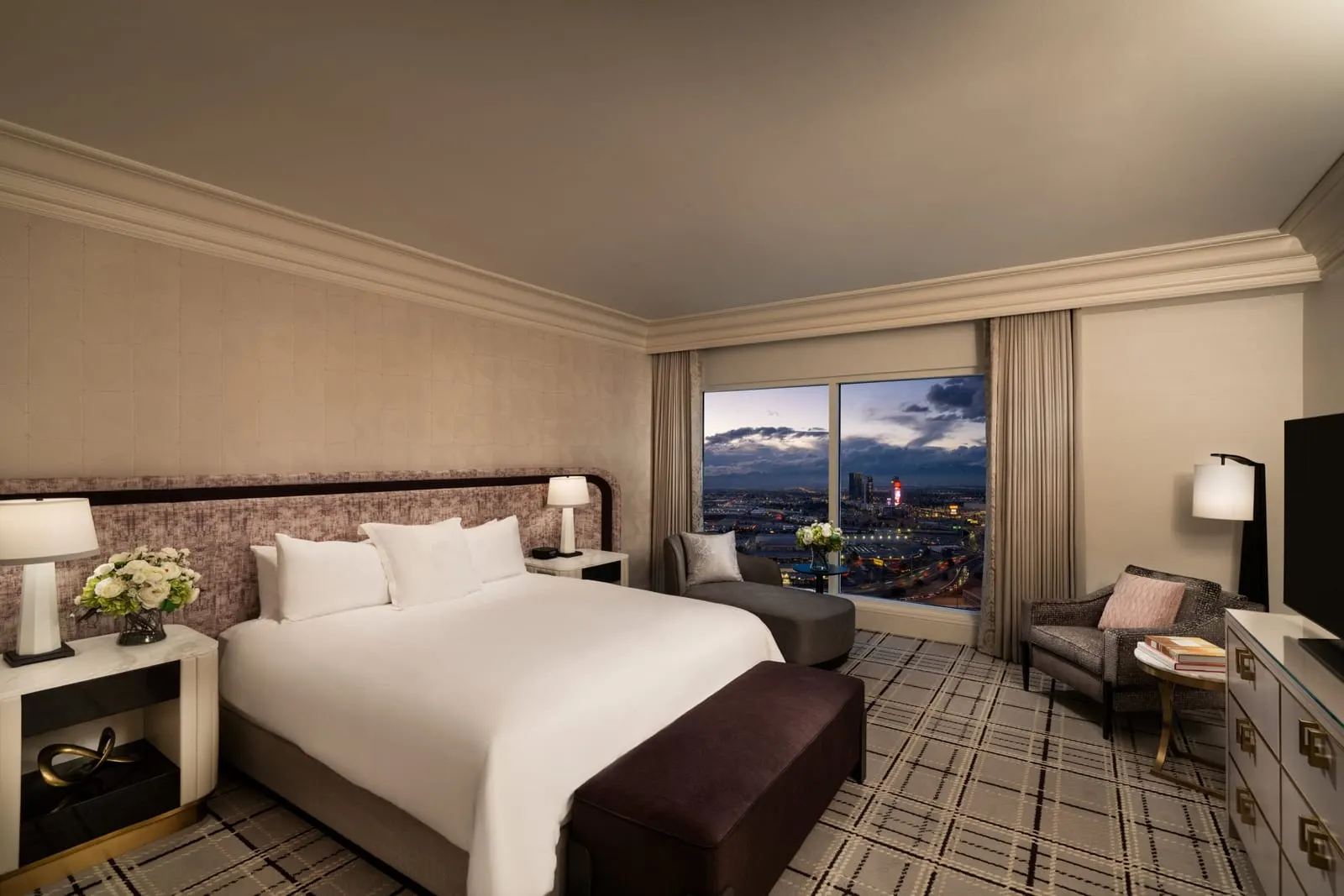 Bellagio Suite at Bellagio: the bedroom, with a king bed, a long upholstered headboard, a bench at the foot of the bed, a chaise longue and an armchair