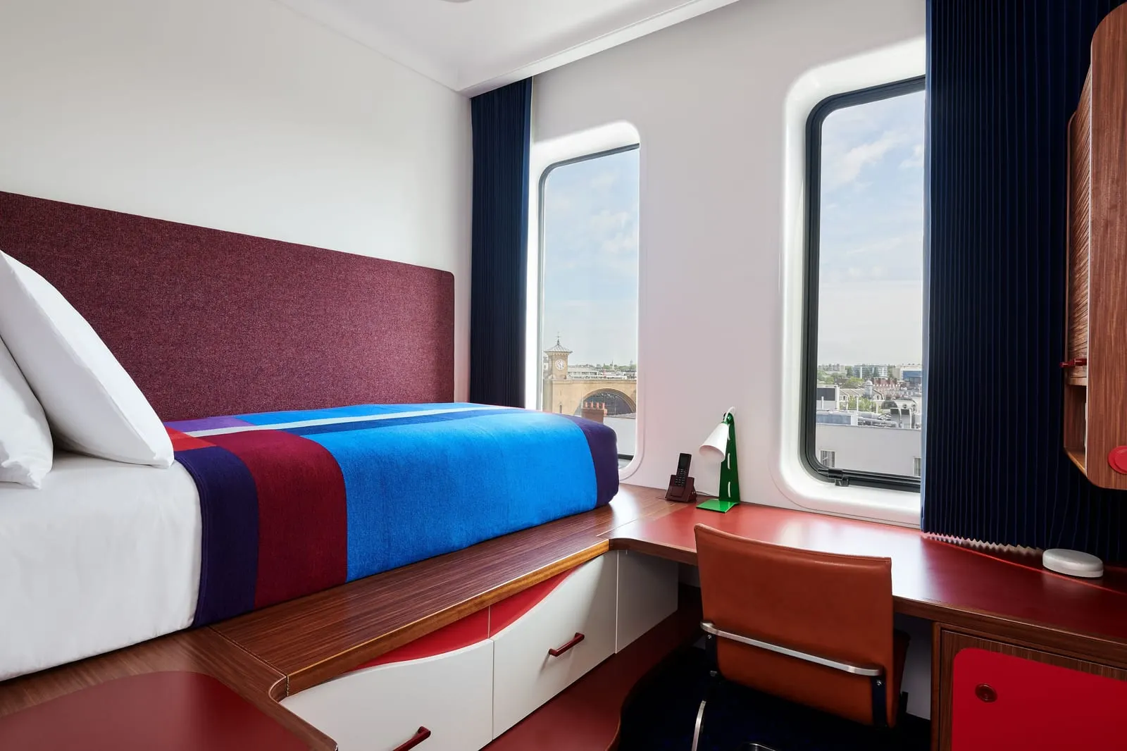 Standard Single at The Standard, London: a single bed with a blue blanket, a built-in desk and two round-cornered windows