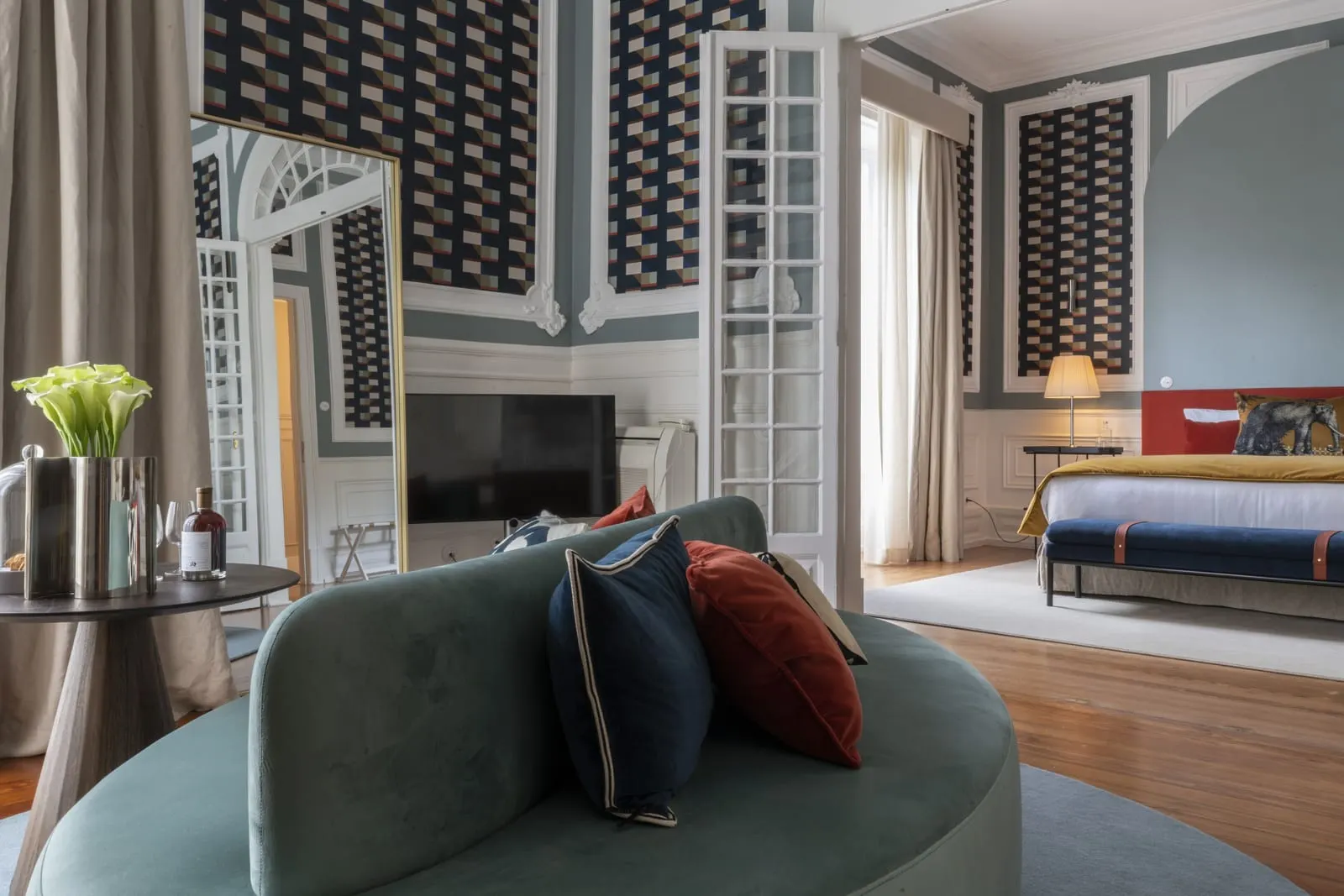 Sublime Suite at Sublime Lisboa: a curved velvet sofa in the sitting room, with the bedroom through open glazed doors
