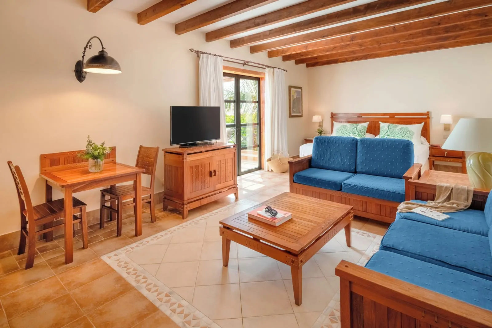 Double Superior at Princesa Yaiza Suite Hotel Resort: a bedroom with a sitting area of blue sofas, a low table and a small dining table under a beamed ceiling