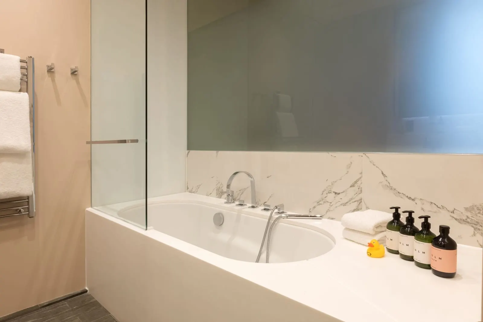 Signature Junior Suite bathroom at Town Hall Hotel: a bath with a marble surround and a glass screen