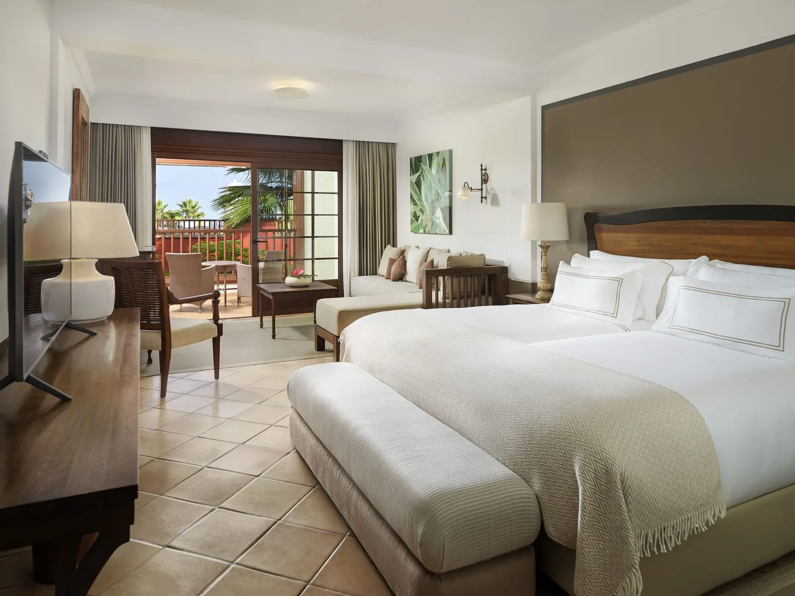 Premier Room at Hacienda del Conde: two beds made up as one, a sofa and doors to a terrace with palms