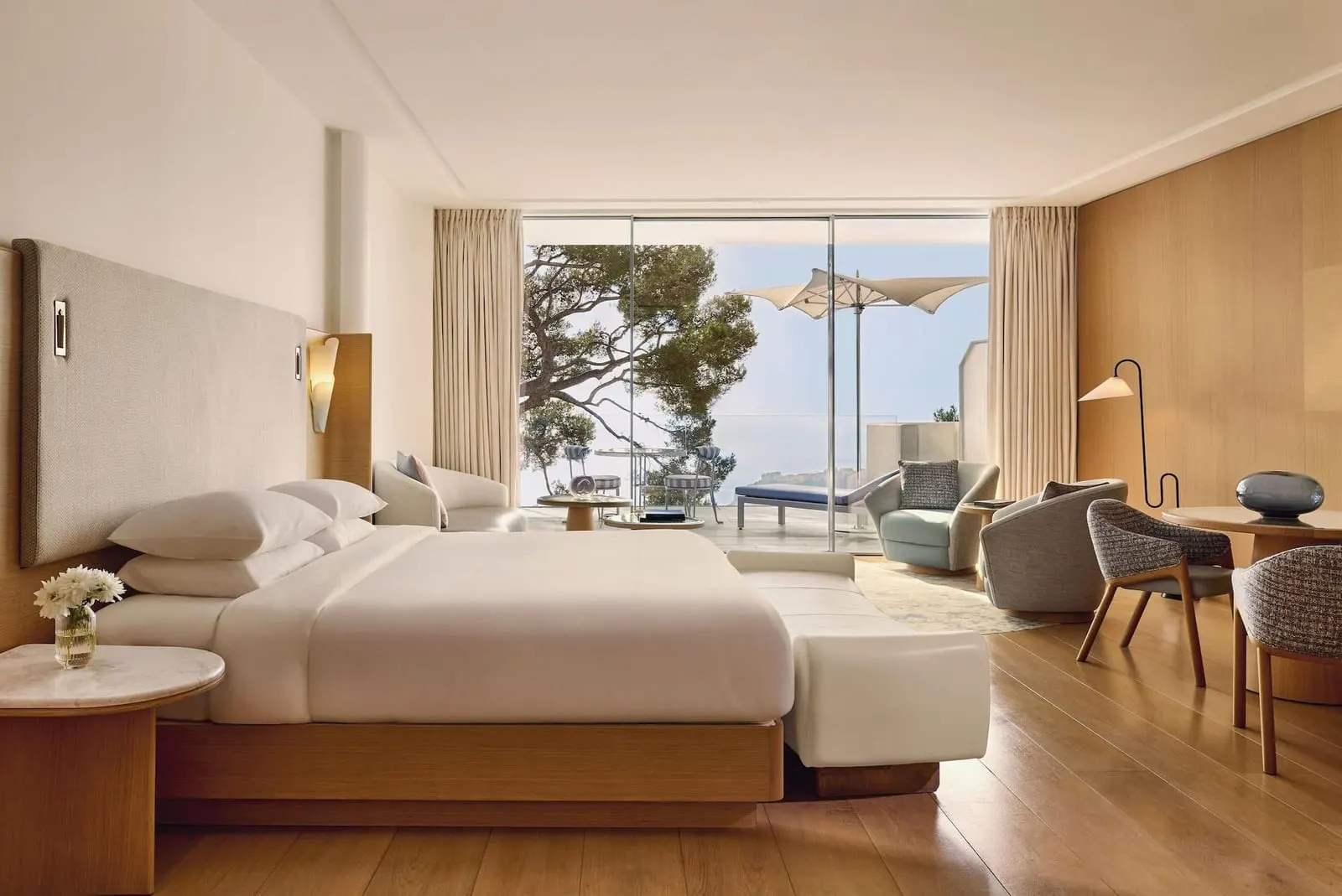 Sea View Junior Suite at The Maybourne Riviera: the bed, a sofa and armchairs, and glass doors to the terrace and the sea