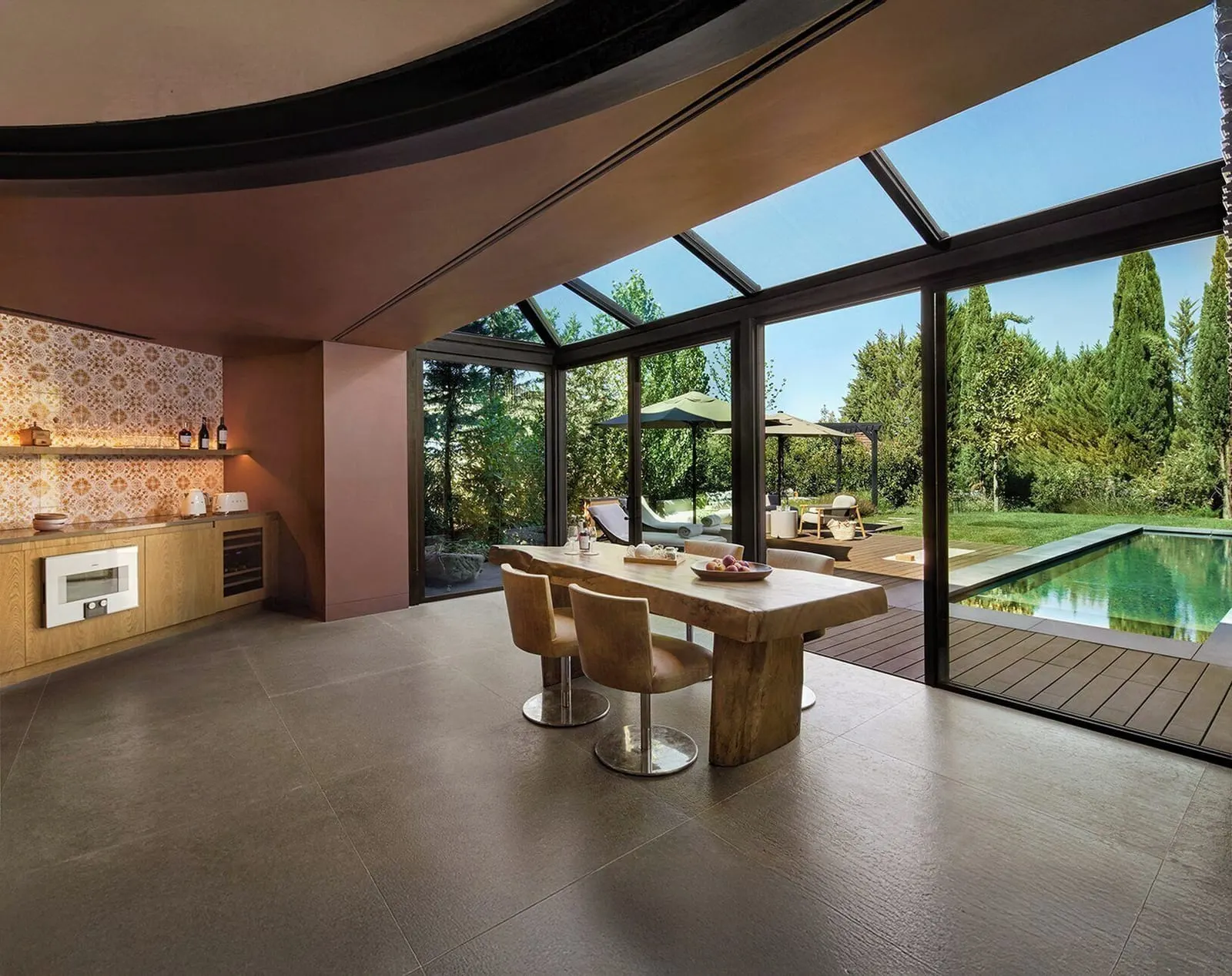 Two Bedroom Pool Villa at Six Senses Douro Valley: a dining table by a tiled kitchen wall, with glass walls onto the pool