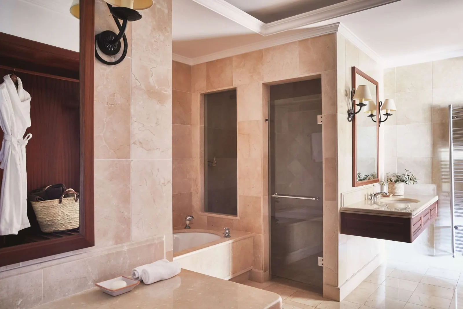 Deluxe Junior Suite at Belmond La Residencia: a marble bathroom with a bath beside a separate glass-doored shower, and a wall-hung vanity under a mirror