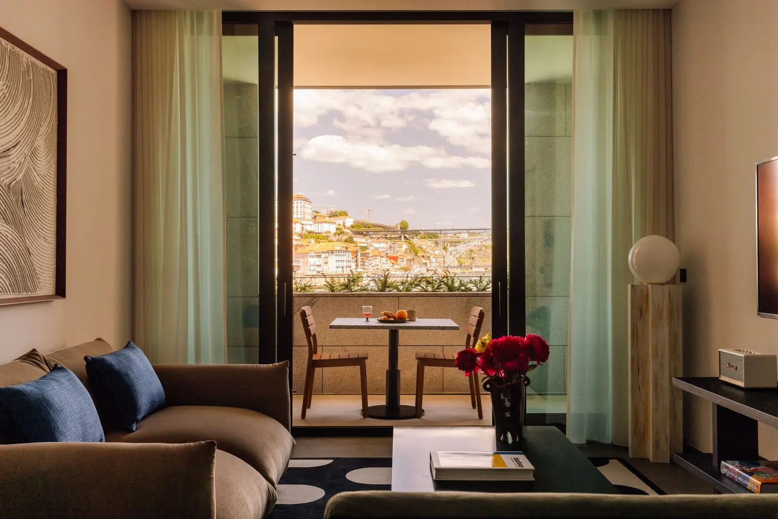 One Bedroom River Suite at The Rebello: the living room, with doors open to a small balcony and old Porto beyond