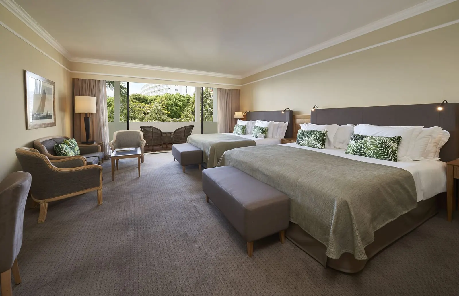 Family Room at The Cliff Bay, by PortoBay: two large double beds side by side, a seating area with armchairs and a sofa, and a balcony with wicker chairs facing tropical trees