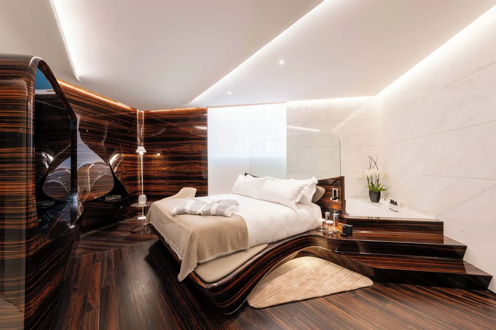 Grand Suite at ROMEO Roma: the bed on a carved ebony base, with steps up to a bath beside it