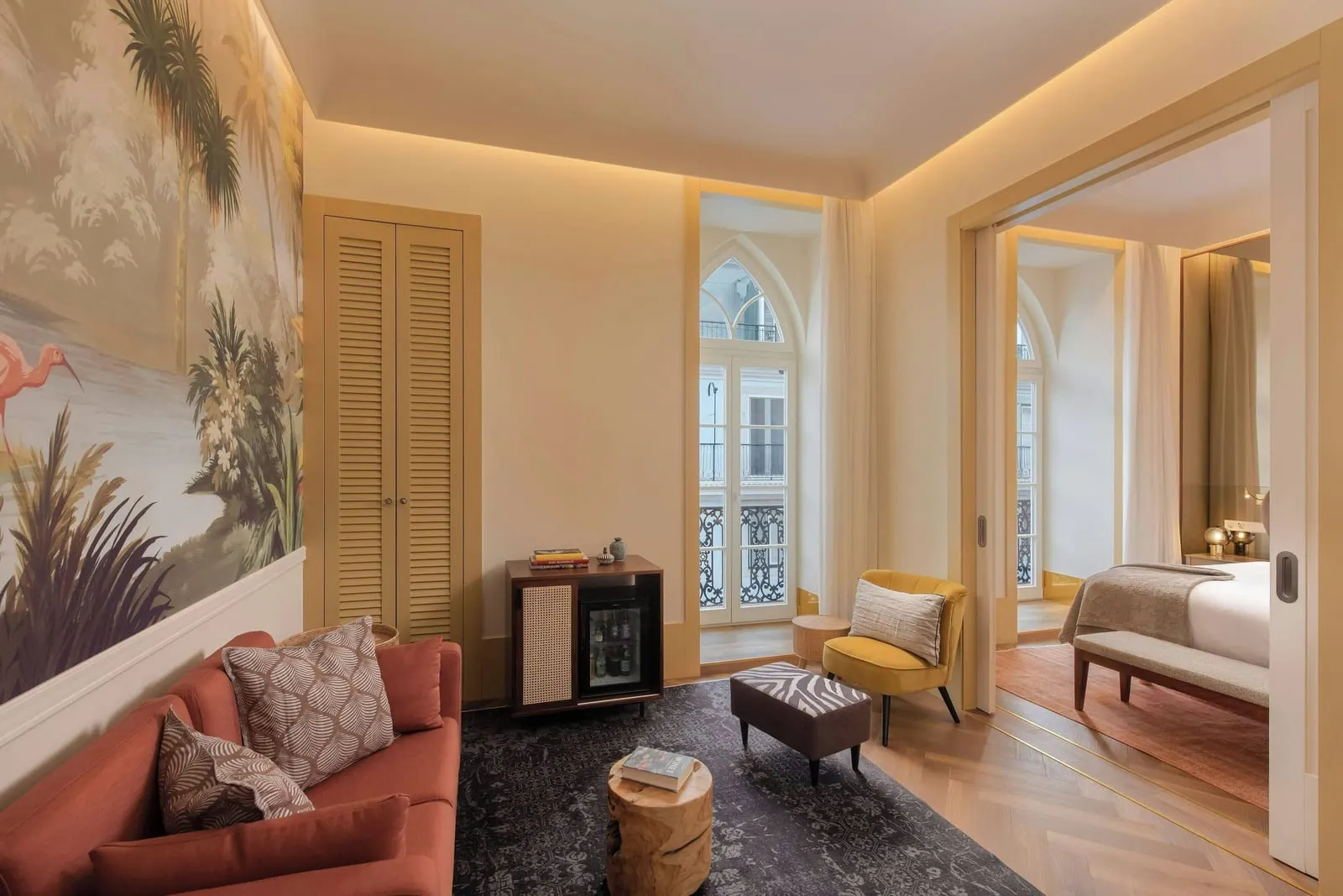 Suite at The Ivens: the living room, with a red sofa and a painted mural, and the bedroom through open doors